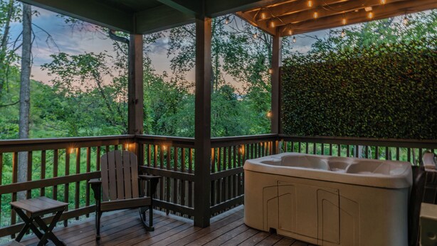 Un espace extérieur abrité comprenant un jacuzzi, une terrasse en bois et des sièges.