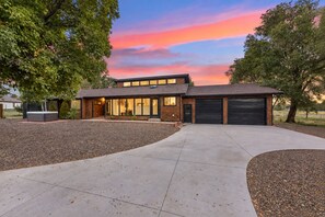 A modern two-story house with a garage, surrounded by a landscaped driveway and trees. - Rare Modern Century Getaway ~ Hot Tub & Game Room (Flagstaff)