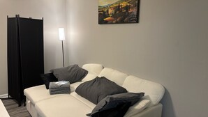 A modern living room with a sofa, pillows, a black cabinet, and a painting on the wall. - Hampton vacation home near Langley AFB (Hampton)