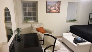 A compact bedroom with a bed, a small sofa, a desk with a chair, and two windows with blinds. - Hampton vacation home near Langley AFB (Hampton)