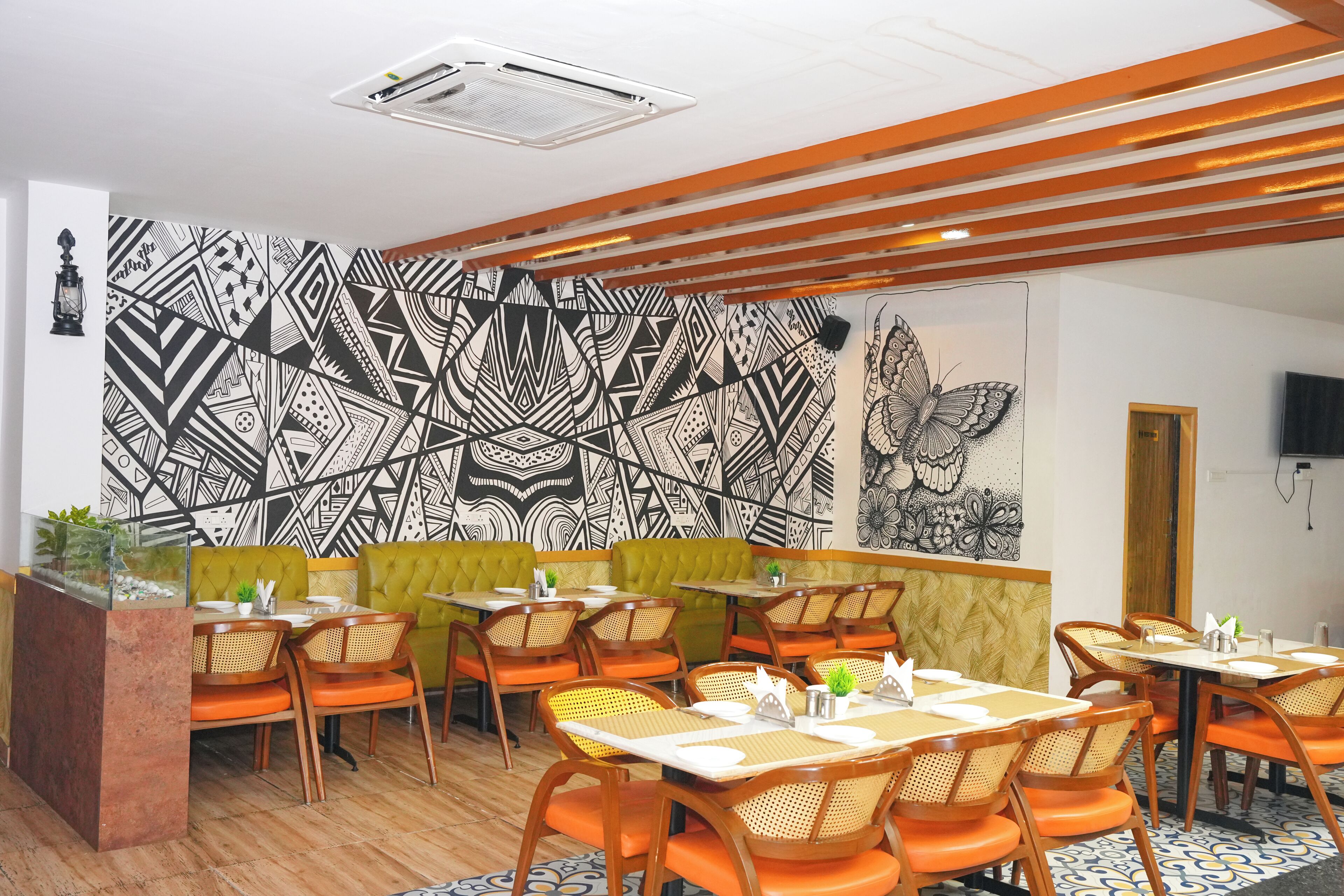 A restaurant with a geometric patterned wall, wooden ceiling beams, and orange seating.