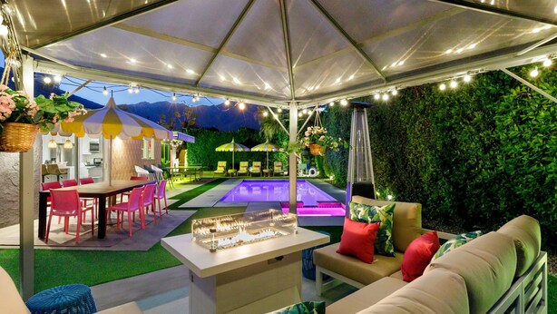 Une terrasse extérieure couverte avec une piscine, des espaces salon et un bar.
