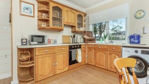 A kitchen with wooden cabinets, a microwave, a toaster, and a washing machine.