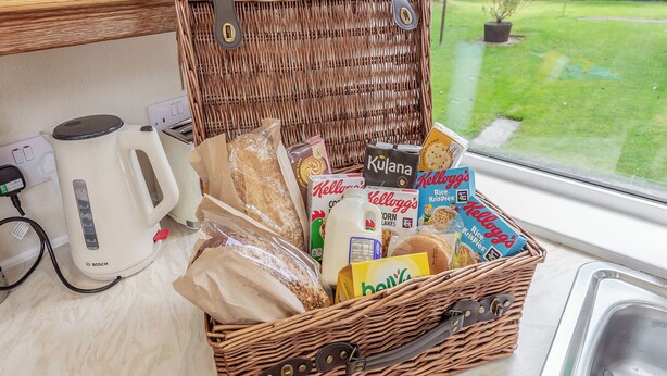 A wicker basket filled with groceries and a white Bosch kettle on a kitchen counter.