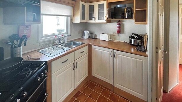 A compact kitchen with a stove, microwave, and sink. - 2 bedroom accommodation in Burnham-on-Sea (Burnham-on-Sea)