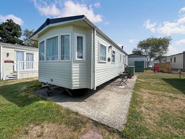 Une maison mobile dotée d’une véranda, d’un petit patio et d’une cour gazonnée.