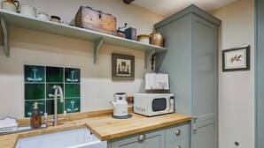 A kitchen with a wooden countertop, a white sink, a microwave, and a cabinet. - 2 bedroom accommodation in Llangadog (Llangadog)