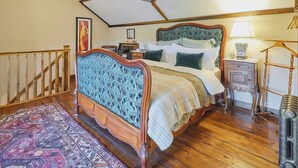 A bedroom with a wooden bed, a nightstand, a lamp, a hanging rack, and a patterned rug. - 2 bedroom accommodation in Llangadog (Llangadog)