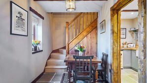 A staircase leading to a dining area with a wooden table and chairs, a patterned rug, and a framed sign on the wall. - 2 bedroom accommodation in Llangadog (Llangadog)