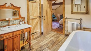 A rustic bathroom with a wooden vanity, a bathtub, and a large mirror. - 2 bedroom accommodation in Llangadog (Llangadog)