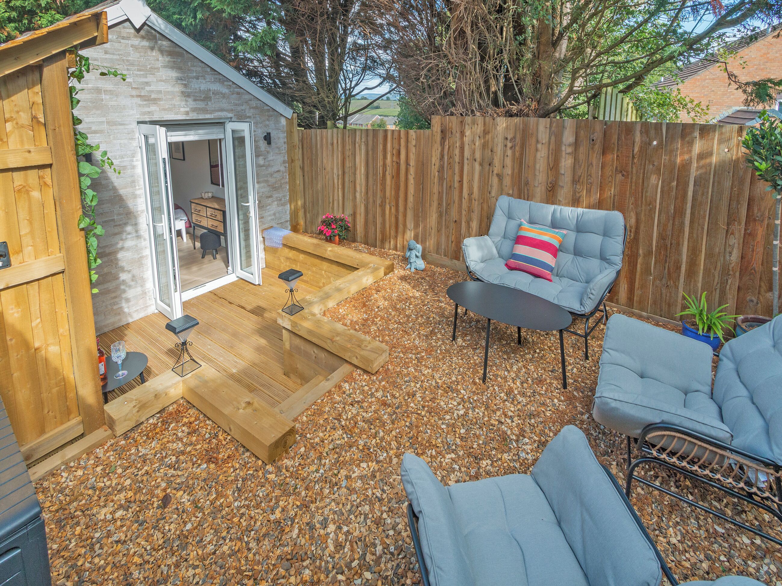 A backyard with a patio area, a wooden fence, and outdoor seating.