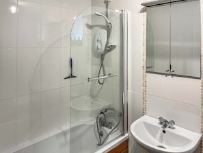 A bathroom with a glass-enclosed shower, a sink, and a mirror.