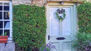 Une charmante maison avec une porte verte, une pancarte d’accueil et un paillasson.