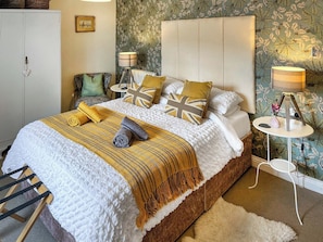 A neatly arranged bedroom with a bed, bedside tables, a chair, and a radiator.