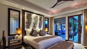 A spacious bedroom with a large bed, a bedside table, and a view of the outdoors.
