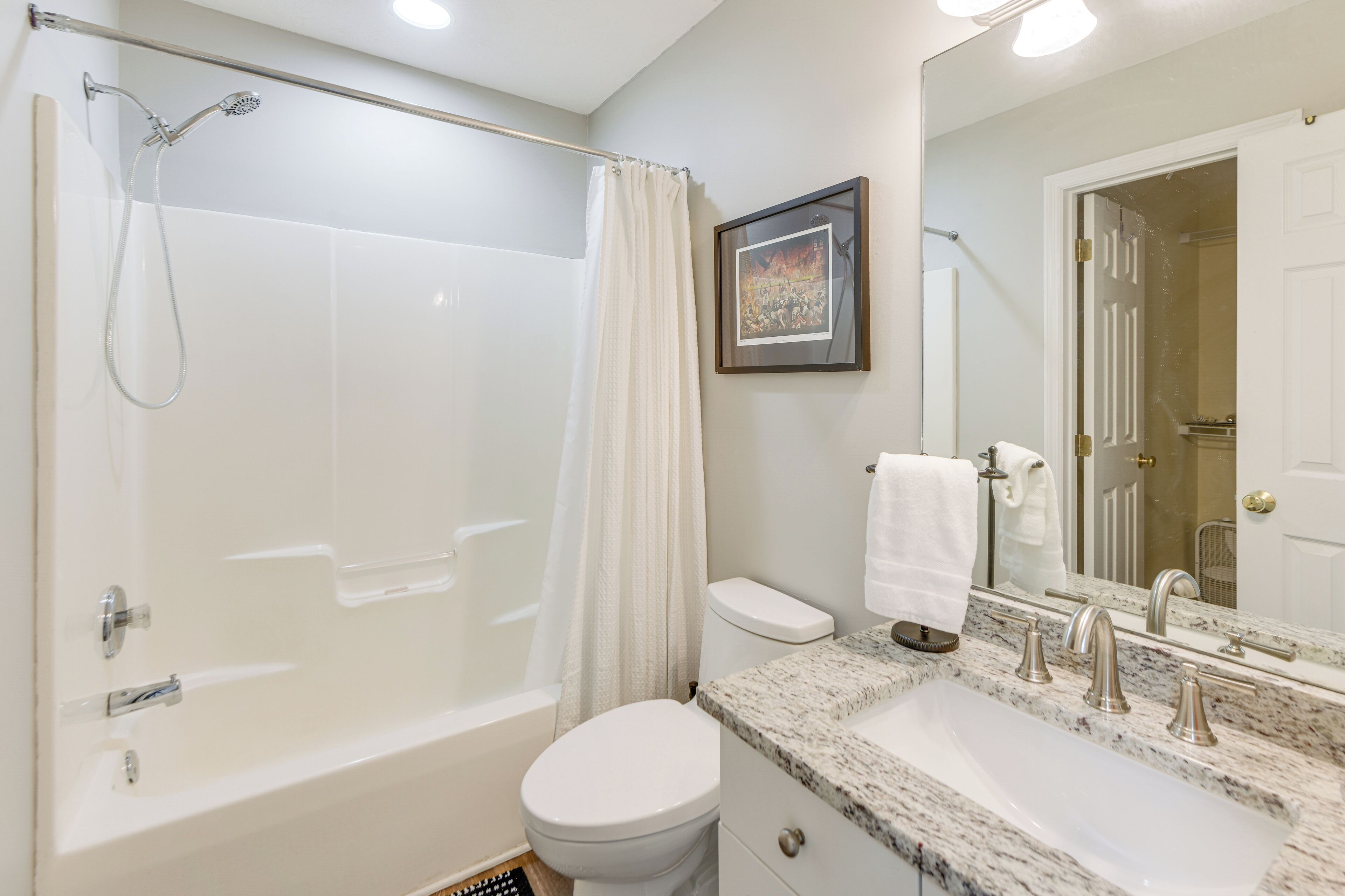 Une salle de bain avec une baignoire, des toilettes, un lavabo et un grand miroir.