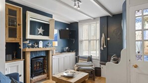 A cozy living room with a fireplace, wooden furniture, and a television mounted on the wall.