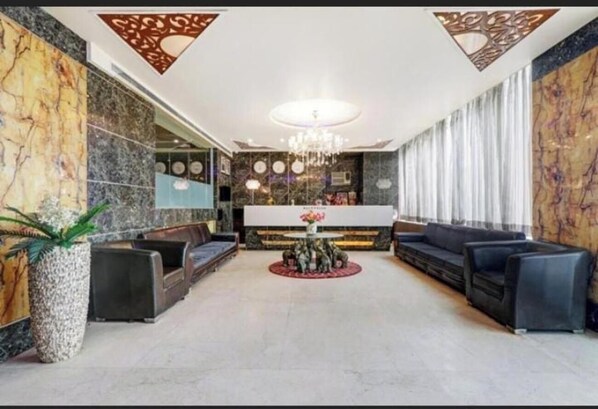 Um hall amplo com área de estar central, um candelabro e um balcão de recepção.