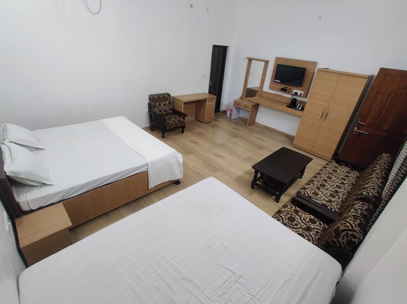 Un dormitorio con dos camas, un sofá, un escritorio, una silla y un armario.