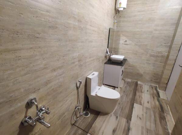 A bathroom with a toilet, a sink, and a shower. - The Vishwanath Palace (Misrikh)
