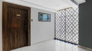 A hallway with a wooden door, a framed artwork on the wall, and a decorative panel with a floral pattern.