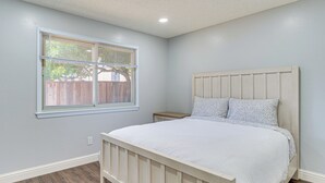 Ein Schlafzimmer mit einem Holzbett, einem Nachttisch und einem Fenster mit Jalousien.