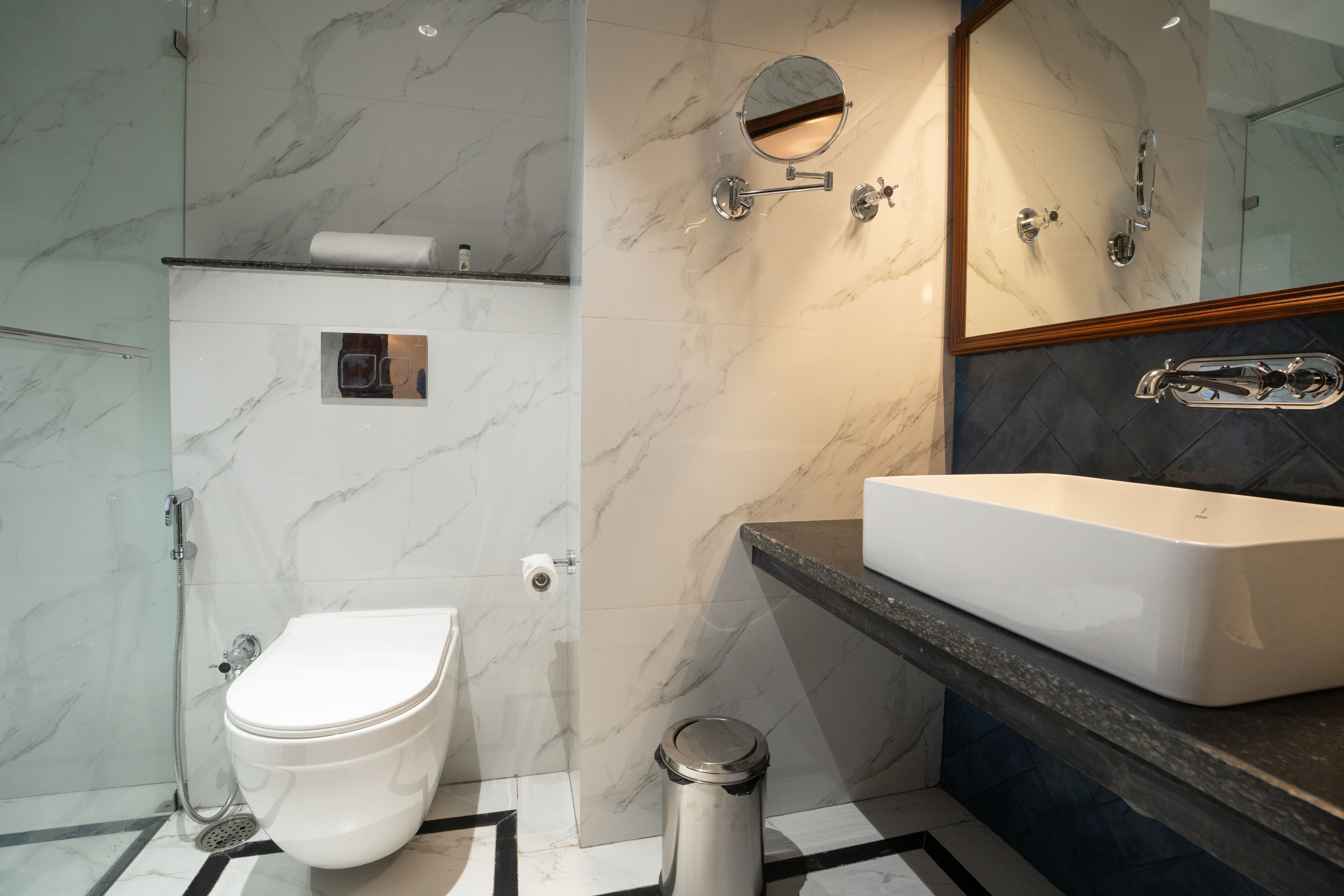 A modern bathroom with a white toilet, a rectangular sink, and a shower area.