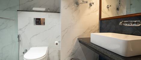 A modern bathroom with a white toilet, a rectangular sink, and a shower area.