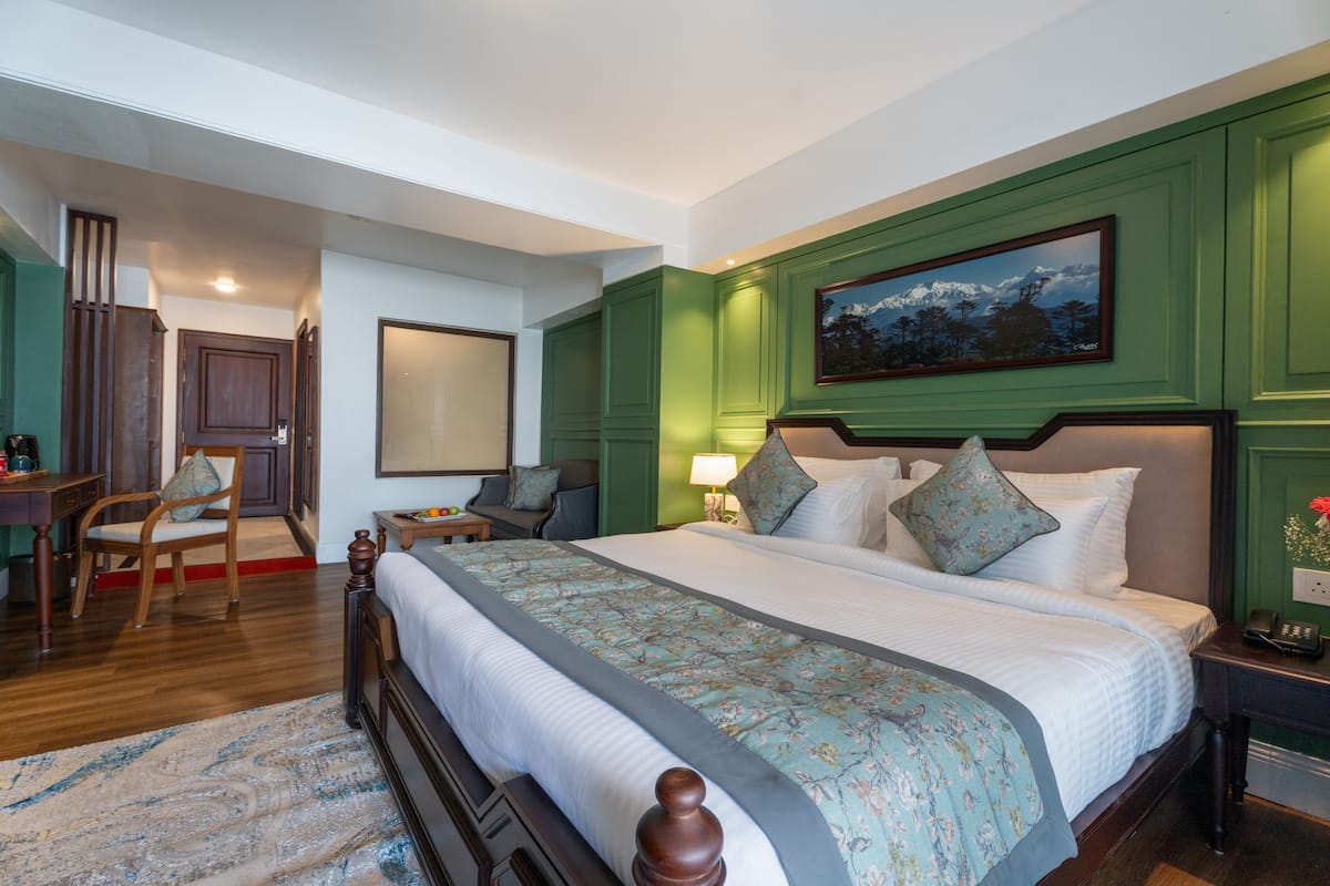 Een hotelkamer met een groot bed, een bureau, een stoel en een schilderij aan de muur.