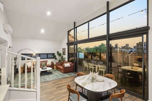 Un interior moderno con zona de comedor, sofá y escalera.