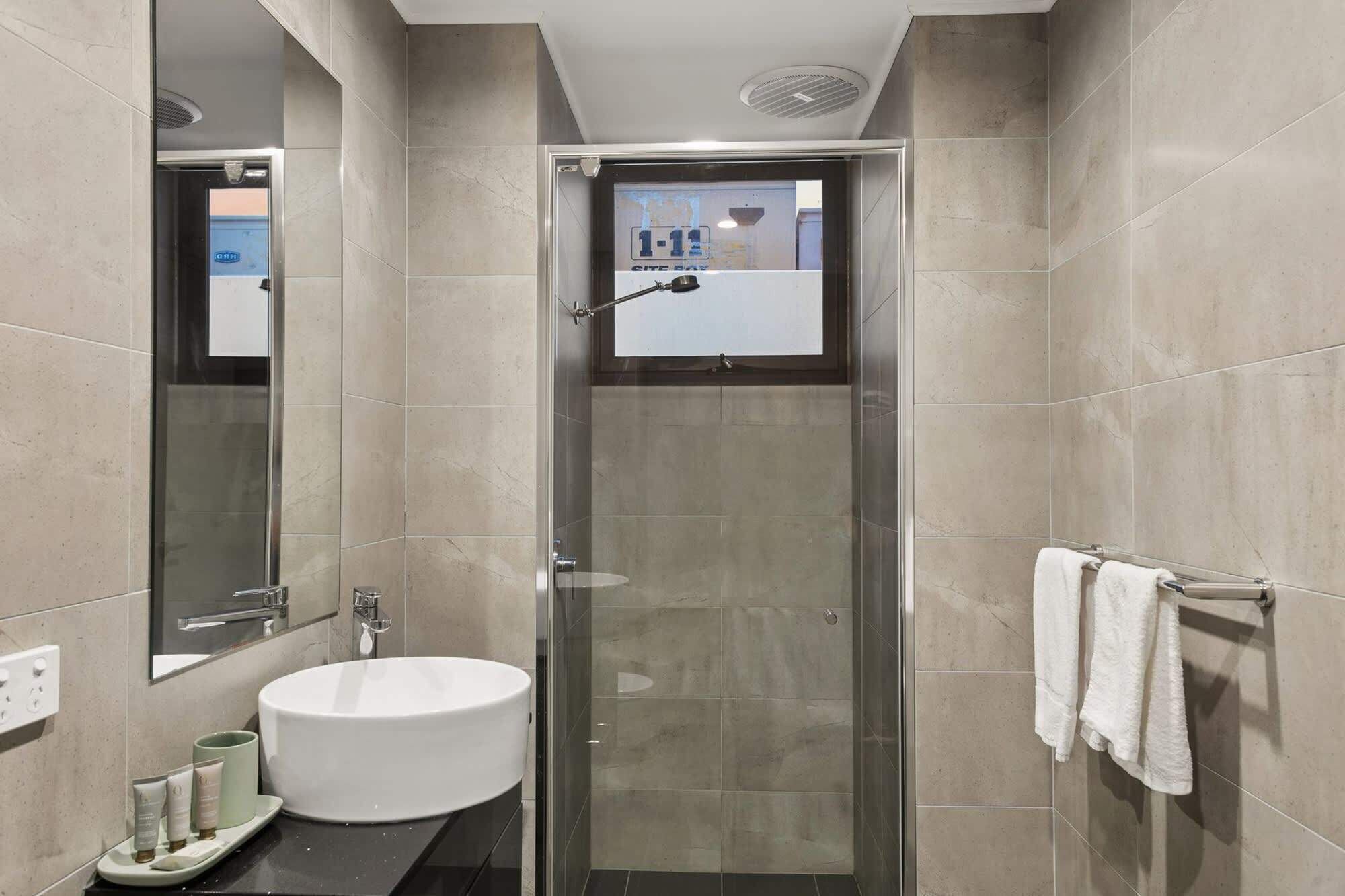 Une salle de bain moderne avec une douche à parois de verre, un lavabo rond et un porte-serviettes.