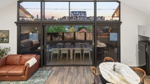 Ein modernes Interieur mit Glastrennwand, Essbereich, Sofa und Küche.