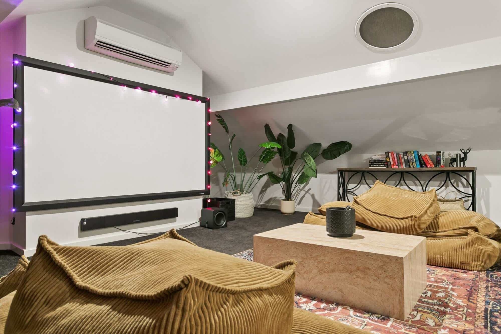 A cozy room with a projector screen, a bookshelf, and a comfortable seating area.