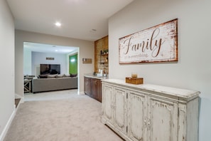 A spacious living area with a large white cabinet, a sofa, and a wall-mounted sign that reads "Family is everything."