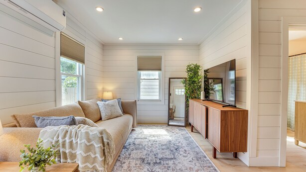 A modern living room with a sofa, TV, and decorative plants.