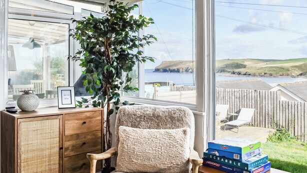 A cozy room with a large window, a wooden cabinet, a plush chair, and a table with board games.