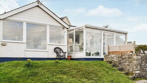 A house with a large glass extension, a lawn, and a stone wall.