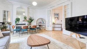 A spacious living room with a fireplace, a large TV, and a dining area with chairs and a table.