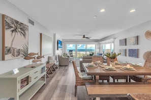 A spacious dining area with a long table, wicker chairs, and a view of the outdoors.