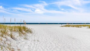 A beach with white sand and sparse grass, a clear blue sky, and the ocean in the background. - Premium Beachfront, Spectacular Views, Walk to Pier 60, Free Parking! ~ 201 Surfside (Clearwater)