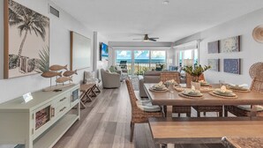 A spacious dining area with a long table, wicker chairs, and a view to the outdoors. - Premium Beachfront, Spectacular Views, Walk to Pier 60, Free Parking! ~ 201 Surfside (Clearwater)