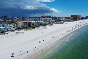 A beach with a clear view of the ocean, a sandy shore, and buildings in the background.