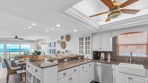 A modern kitchen with white cabinetry, granite countertops, and a ceiling fan. - Premium Beachfront, Spectacular Views, Walk to Pier 60, Free Parking! ~ 201 Surfside (Clearwater)