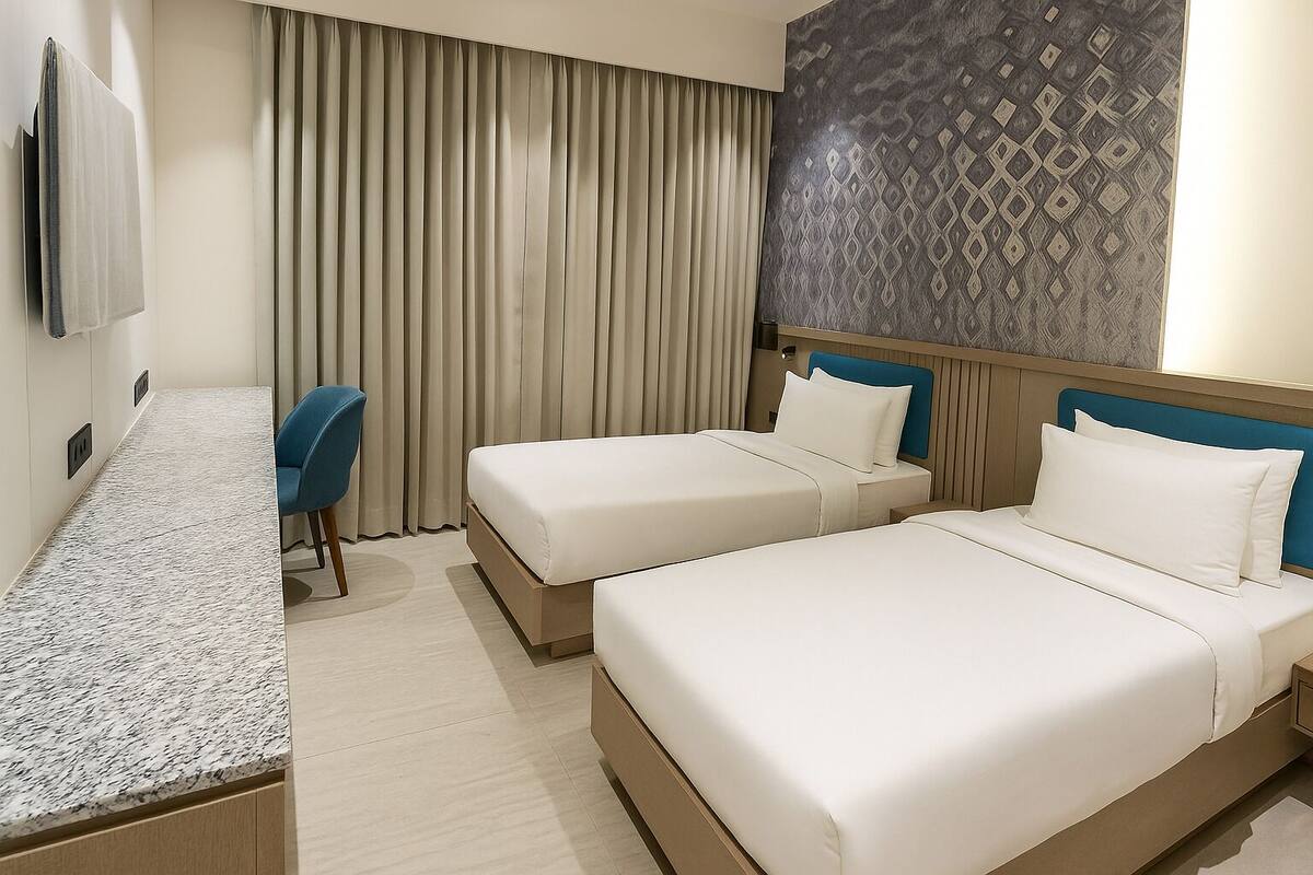 A hotel room with two beds, a desk, a chair, and a large window with curtains.