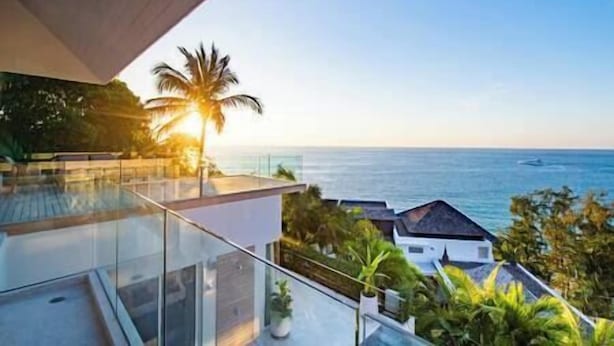 Un bâtiment moderne doté d’un balcon en verre offrant une vue sur la côte.