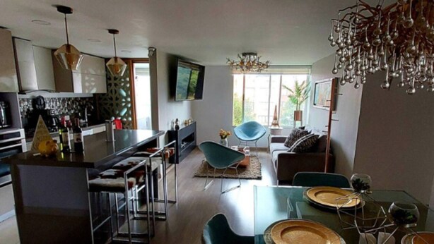 Una cucina moderna con isola centrale, sgabelli da bar e zona pranzo con tavolo e sedie in vetro.