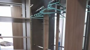 Armadio a muro con scaffali in legno, uno specchio e una barra appendiabiti.