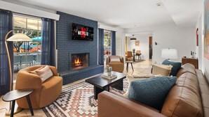 Ein modernes Wohnzimmer mit Kamin, Netflix-Fernseher und bequemen Sitzmöglichkeiten.