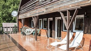Un edificio in legno con veranda coperta, posti a sedere all'aperto e un'amaca.