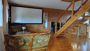 A room with a wooden staircase, a large screen, and a floral-patterned chair.